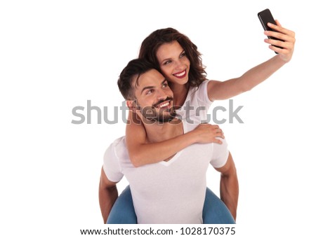 casual happy couple taking a selfie picture with their phone on white background