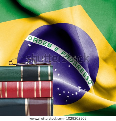 Education concept - Stack of books and reading glasses against National flag of Brazil