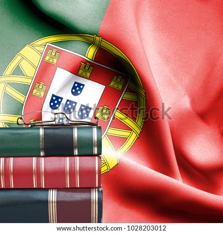 Education concept - Stack of books and reading glasses against National flag of Portugal