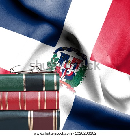Education concept - Stack of books and reading glasses against National flag of Dominican Republic
