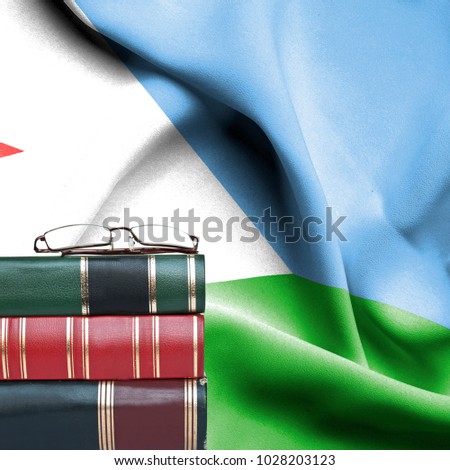 Education concept - Stack of books and reading glasses against National flag of Dijbouti