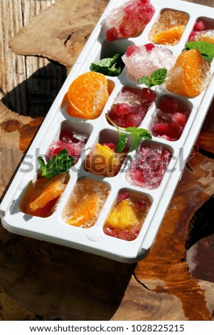 cubes with frozen fruit and berries in a container to freeze ice.
