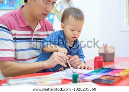 Cute little Asian 18 months / 1 year old toddler baby boy child painting with brush and watercolors, kid painting with father at home ,Creative play for toddlers concept