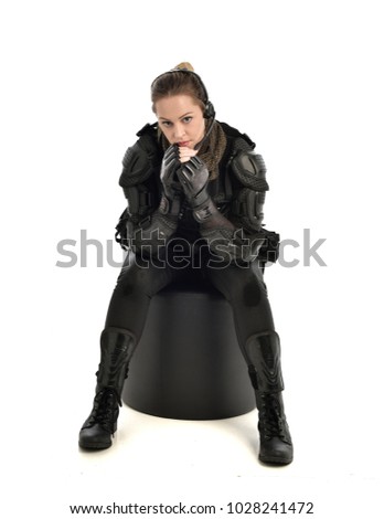 full length portrait of female wearing black  tactical armour, crouching pose, isolated on white studio background.
