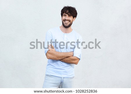 Portrait of happy young man with beard smiling by wall
