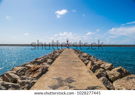 The beacon at the end of the path in the Bar Marina. Sunny day on the Adriatic Sea, Montenegro.   Royalty-Free Stock Photo #1028277445