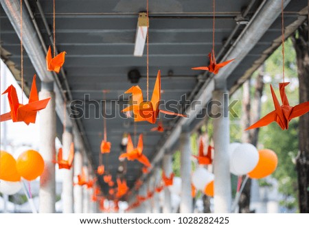 Orange paper bird is hung by a rope.