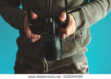 Photographer holding full frame sensor DSLR camera and reviewing taken pictures