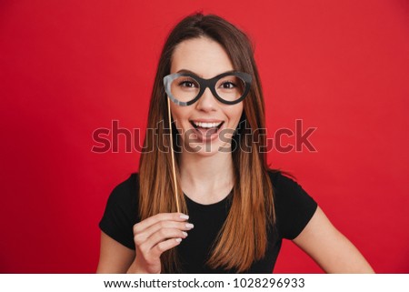 Portrait of a funny girl having fun with fake eyeglasses isolated over pink background