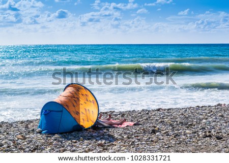 Tourists are laying down in a tent on the beach in Bar, Montenegro, Adriatic Sea. Sunny day with lots blue color against orange tent.  Royalty-Free Stock Photo #1028331721