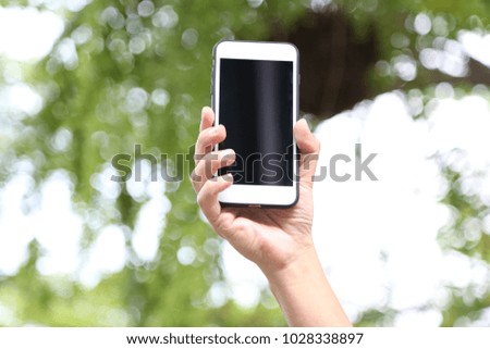 a hand of businessman is holding a smartphone in the park with technology of communication