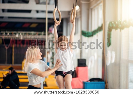 Mother helping her daughter to play sports on gymnastic rings
