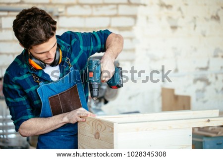 Carpenter drills a hole with an electrical drill