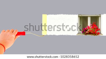 Person painting a window with flowers on a white wall with a roller brush