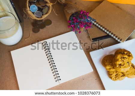 Notebooks placed on the desk with milk and cookies, beautifully decorated with dried flowers, make it look more attractive and have space on paper.
