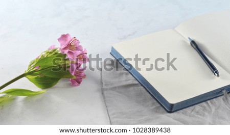 Open notebook with flowers on white marble background. Flat lay. Top view. Copy space.
