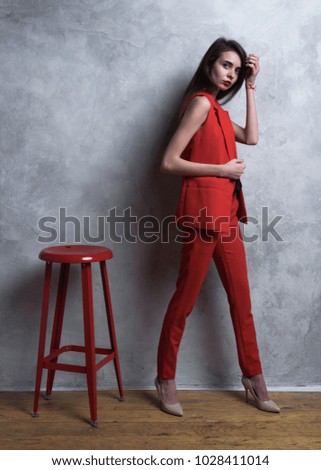 girl model in a red suit against a gray background. Studio photography.