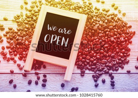We are open blackboard with coffee beans on wood background. copyspace for advertising