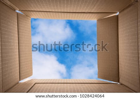 Thinking Outside the Box. Conceptual Image about Creative thinking: photo of the inside of an Open Cardboard Box with a Blue Sky with Clouds in Background