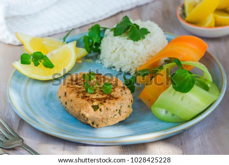 Healthy salmon burger with rice, carrot and cucumber salad