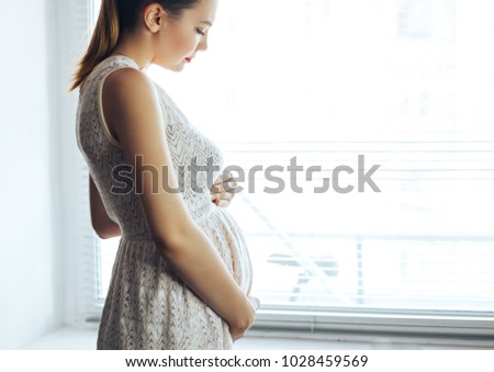 pregnancy, rest, people and expectation concept - close up of happy smiling pregnant woman touching her belly at home