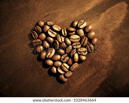 Coffee beans at breakfast shaped in heart on wood grain background.