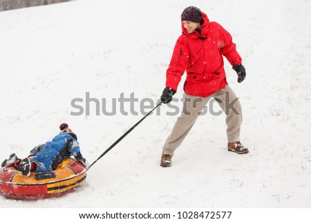 Photo of man riding his son on winter day