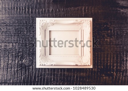 Black wooden background with heart decoration and white frame for text. Copy space.