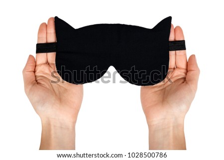 Black cotton mask for sleep in hand. Isolated on white background. Cat shape.