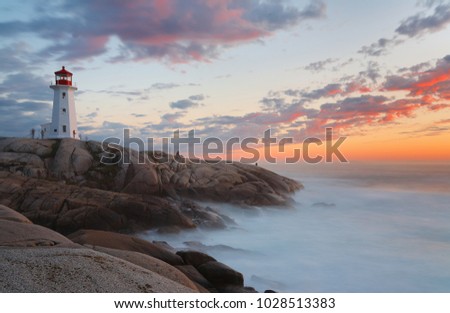 Beautiful Peggy Cove Light House with Sunset, Nova Scotia, Canada. Photo shows tourists watching sunset.