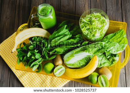Blended green smoothie with ingredients on wooden table selective focus. Raw food.