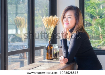 Asian woman relaxing with dry flower on wooden table near the window in the room