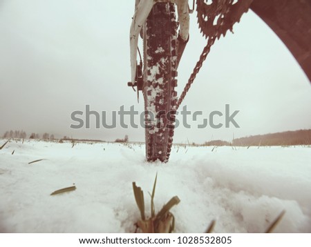 Low ankle photo of rear hweel of mtb in snowdrift. Picture taken within winter bike trip in free landcape.
