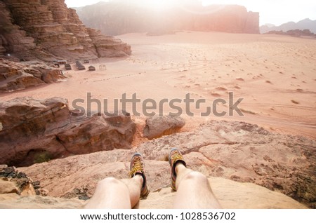 
    Jordan national park Wadi Rum desert. Beautiful view and panoramatic picture of man legs and outdoor shoes. Natural background. Sunset in a desert. 