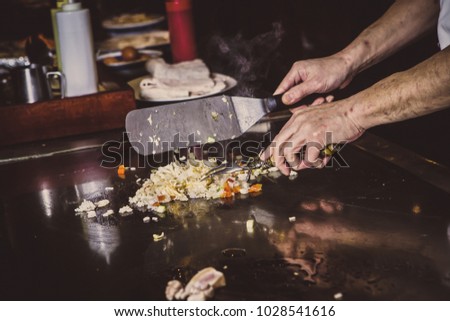 Picture of the hands of the cook cooking Thai food with rice, vegetables and eggs.