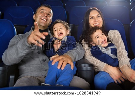 Shot of a happy loving family enjoying watching a comedy or cartoon at the cinema laughing cheerfully parents watching movies with their two twins sons love entertainment bonding parenting childhood.
