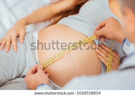 Monthly checkup. Scaled up look on male doctor measuring bump of an expectant mother during a regular appointment.