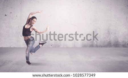 A beautiful young hip hop dancer dancing contemporary urban street dance in empty clear grey wall background concept.