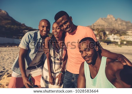 Group of friends taking selfie on the seashore. Young people having great time together at the beach.