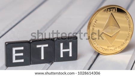 Ethereum cryptocurrency coin with ETH text on white wooden table top
