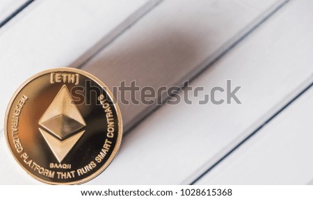 Ethereum cryptocurrency coin on white wooden table top

