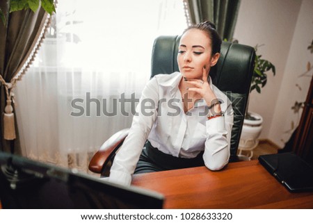 Image of professional businesswoman working at her office via laptop, young female manager using portable computer device while sitting at modern loft, flare light, work process concept
