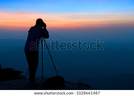 Photographer takes a photo above high mountain landscape at twilight.