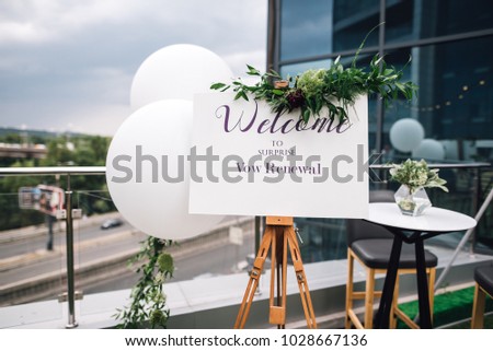 Closeup of easel with white Welcome sign on frame stands on the roof top during wedding party. Vow renewal