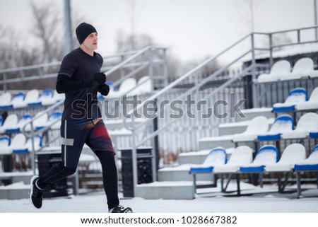 Image of running athlete in black clothes at stadium