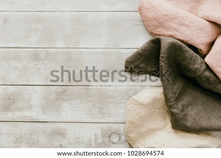 Three natural linen napkin on wooden background. Pastel tones 