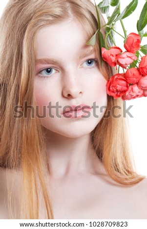 Portrait of young redheaded girl on a white background. Girl with a twig of roses in her hair. Vertical photo. Close up