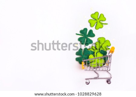 Shopping trolley with four-leaf clover on whte background. Copy space. St.Patrick's day holiday sale.