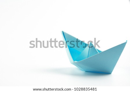 Blue paper ship isolated on white background. Paper craft and origami. Close up. 