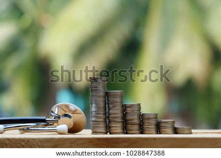 close up stack of coins and stethoscope on old wood table, green nature copy space background for text, saving money for healthcare, manage for success business concept